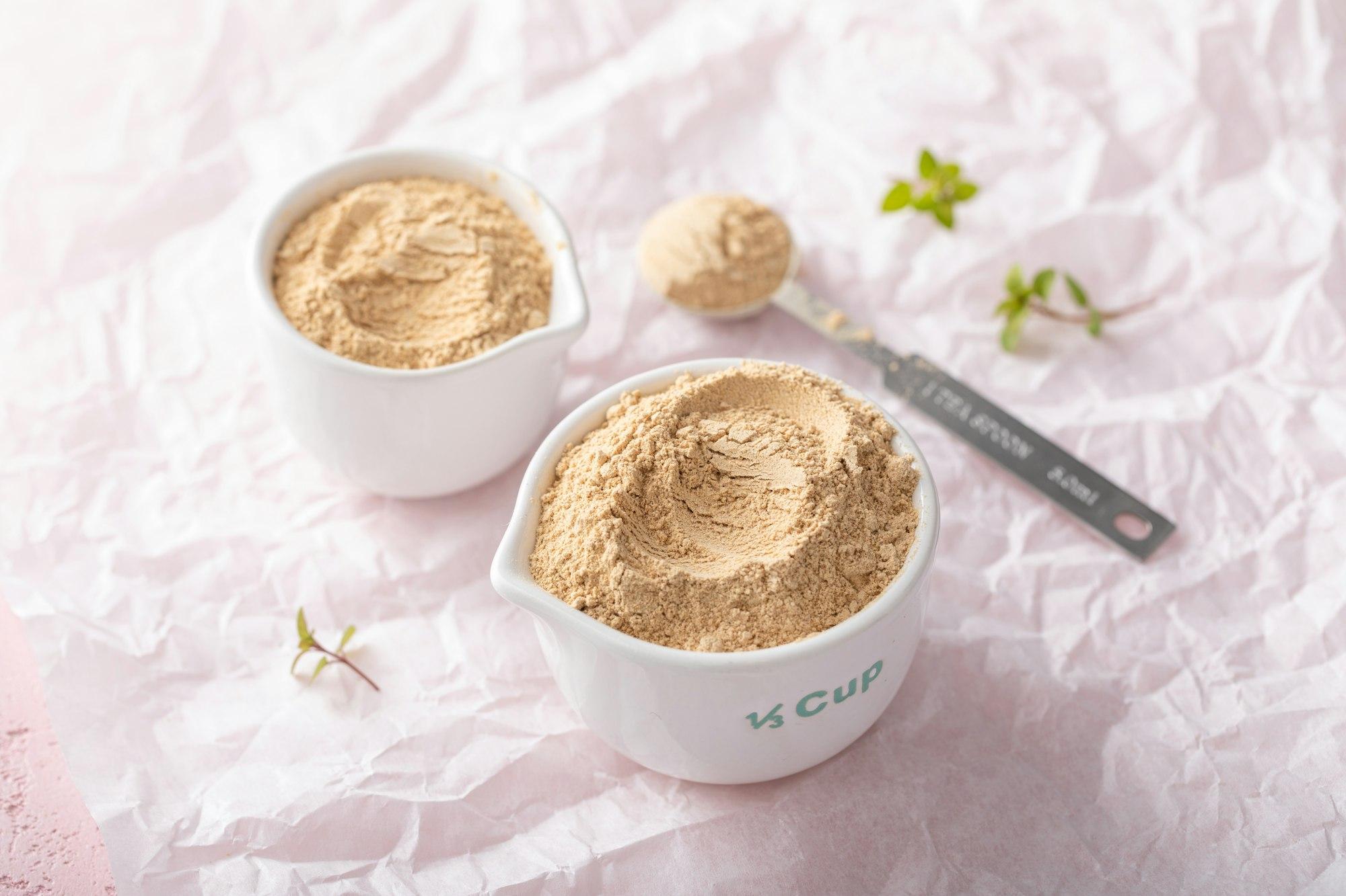 Maca powder in measuring cups and a spoon