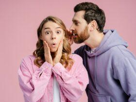 Portrait of attractive excited woman looking at camera man whispering secret in her ear