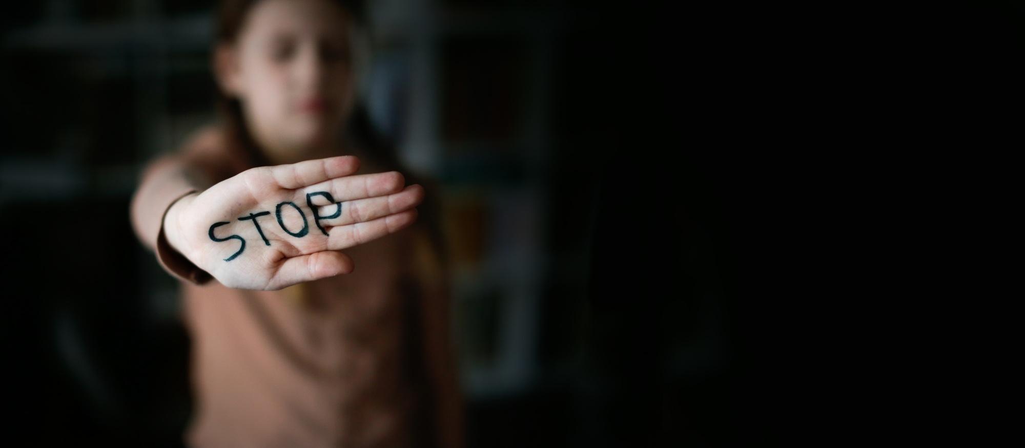 Stop - text on the palm of the hand and gesture. Child girl is closed by hand with inscription stop